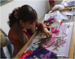 一名来自Nanzheng示范合作社的社员和她的刺绣作品。这个绣花刺绣作品很好地展示了她的才华。